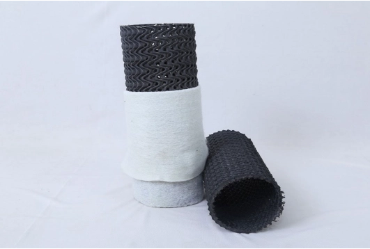 permeable drainage pipe consisting of polymer drainage core wrapped with nonwoven geotextile filter fabric for subsurface water management