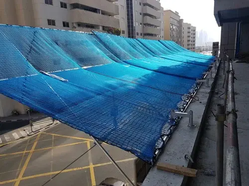 System safety net installed on high-rise building perimeter for fall protection and overhead construction safety