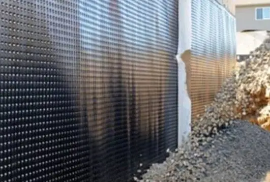 Dimple board installed for drainage and waterproofing protection along foundation wall